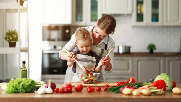 szczęśliwa matka rodziny z synem dziecka przygotowuje sałatkę warzywną - domestic kitchen people fun lifestyles zdjęcia i obrazy z banku zdjęć