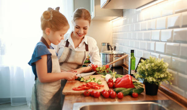 happy family mother with child girl preparing vegetable salad - family mother domestic life food imagens e fotografias de stock