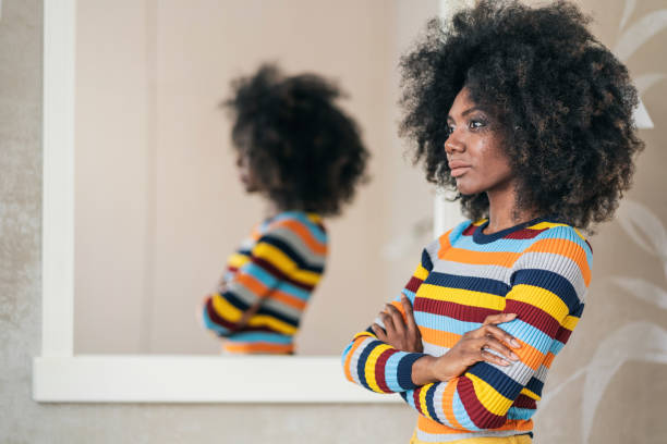 istock Afro Woman standing in front on the mirror 1169296172