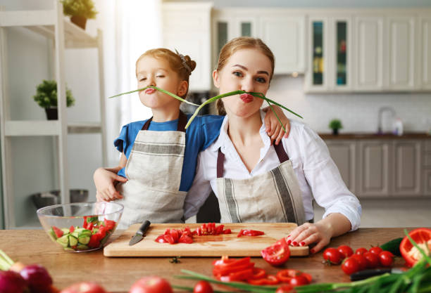 happy family mother with child girl preparing vegetable salad - family mother domestic life food imagens e fotografias de stock