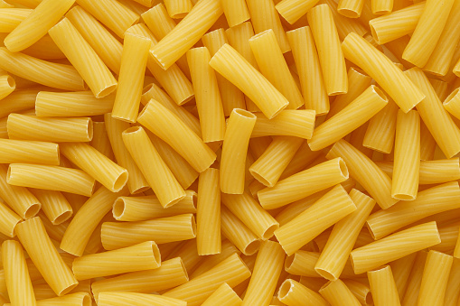 Dry uncooked tortiglioni or rigatoni pasta as a background. Flat lay.