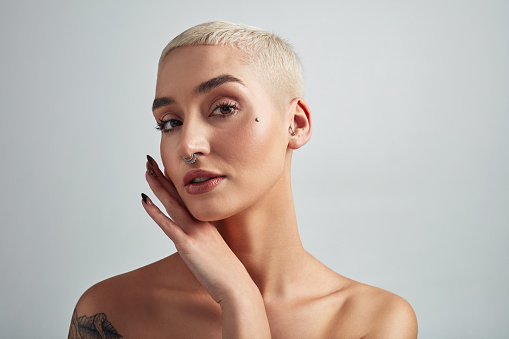 Portrait of a beautiful young woman posing against a grey background