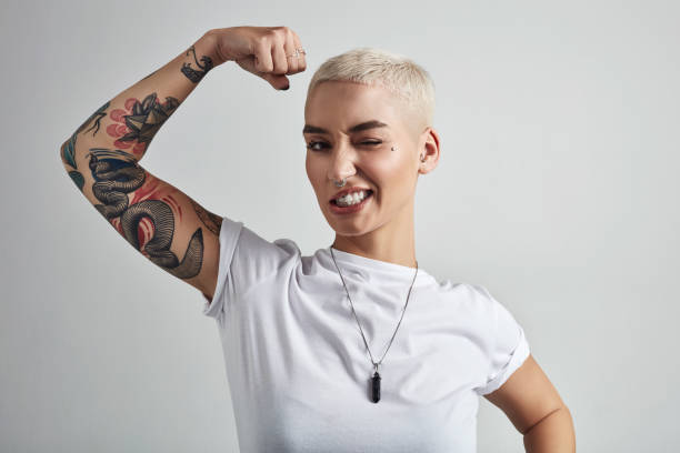 Bringing out the big guns Shot of an attractive young woman flexing her biceps against a grey background shorthair stock pictures, royalty-free photos & images