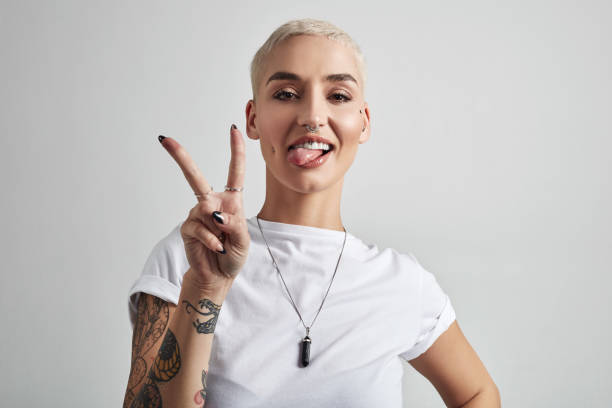 Peace out world Portrait of an attractive young woman showing the peace sign against a grey background v sign stock pictures, royalty-free photos & images