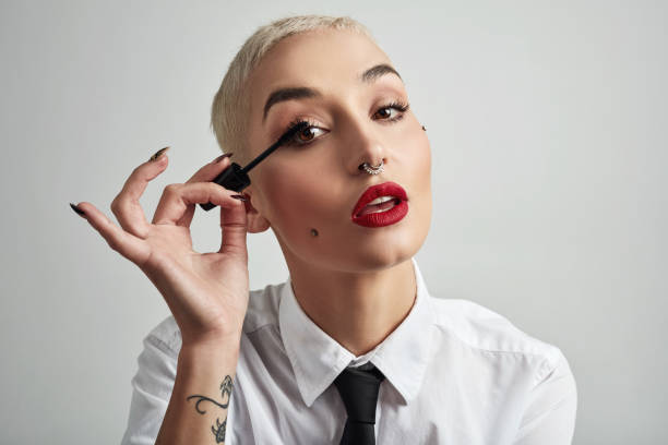 Lush lashes are the way to go Portrait of an attractive young businesswoman putting on mascara against a grey background woman necktie stock pictures, royalty-free photos & images