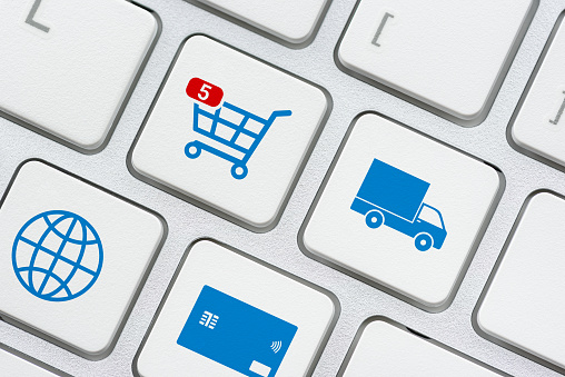 Online shopping / ecommerce and retail sale concept : Shopping cart, delivery van, credit card, world globe logo on a laptop keyboard, depicts customers order things from retailer sites using internet