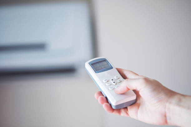 istock Air conditioner inside the room with woman operating remote controller. / Air conditioner with remote controller 1169310180