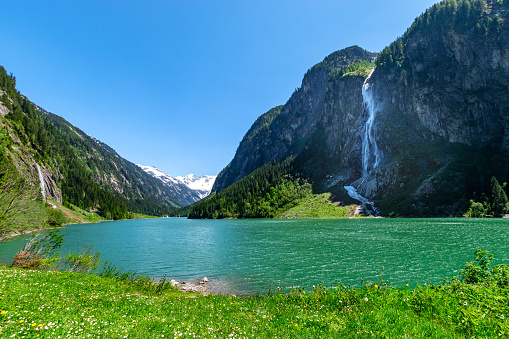Mountain landscape with clear turquoise lake and waterfall in the Alps. Zillertal Alps Nature Park, Austria, Tyrol.