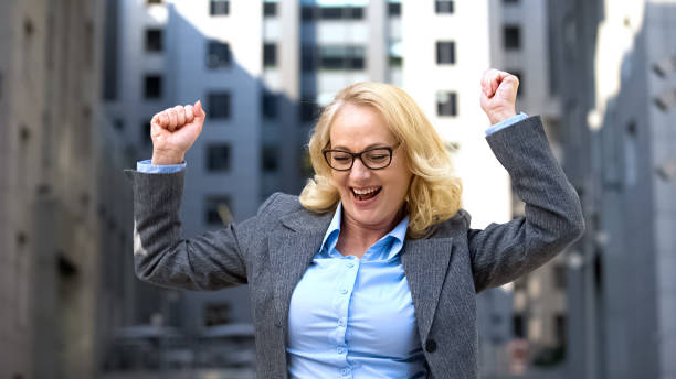 istock Excited mature female boss in formal suit dancing outdoors, work motivation 1169312947