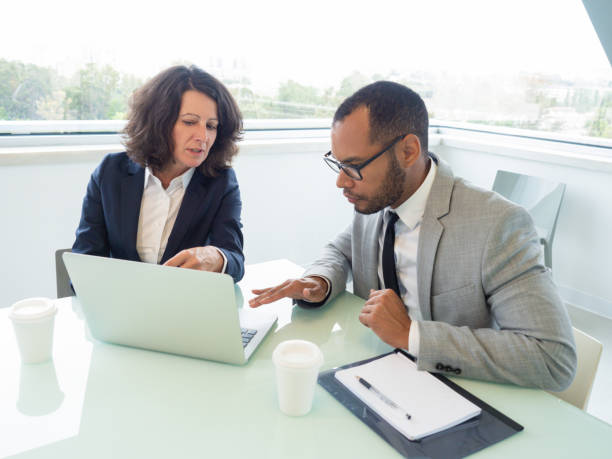 istock Female mentor teaching male intern 1169313584