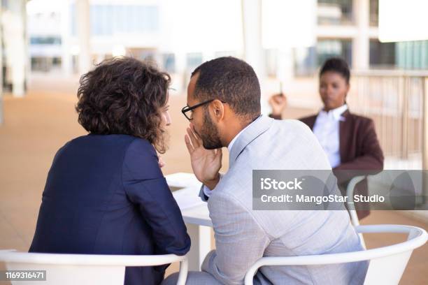 Employees Gossiping About Young Female Colleague Stock Photo - Download Image Now - Gossip, Whispering, Office