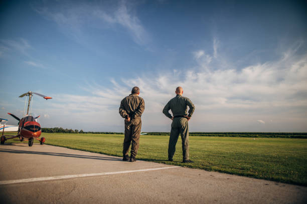 istock Two pilots on a meadow by the propeller airplane 1169316751