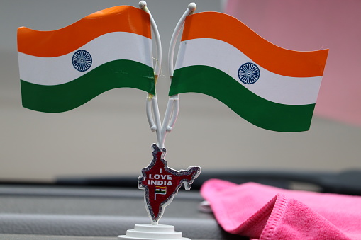Two Indian flag stand on car dashboard