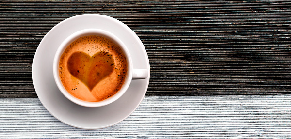 Coffee cup on old wooden black and whit background with heart shaped cream