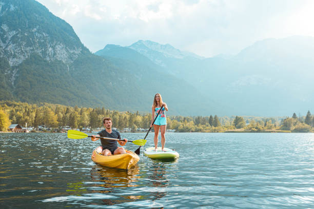 young woman paddleboarding and young man in a kayak on the lake - lake bohinj imagens e fotografias de stock