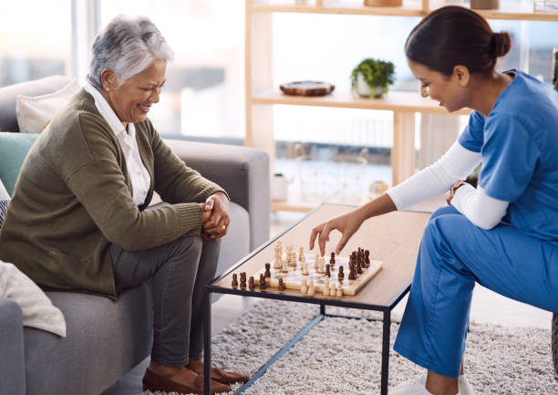 Playing games are a great way to keep the mind active Shot of a young nurse playing chess with a senior woman in a retirement home keep up the great work stock pictures, royalty-free photos & images
