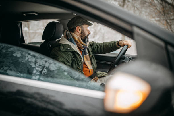istock Man driving car in snowy forest 1169325051