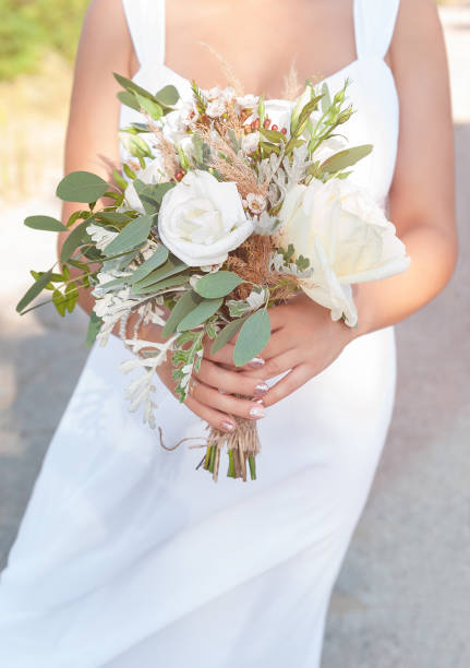 istock Bride holds a white wedding bouquet, close up. 1169325902