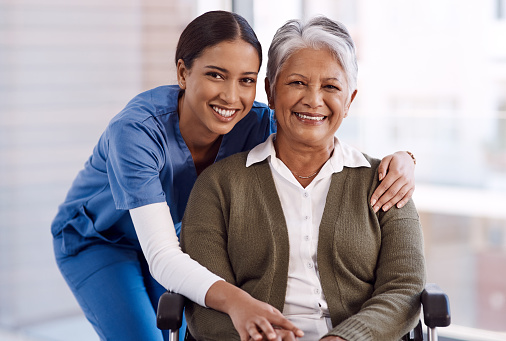 Portrait of a young nurse caring for a senior woman in a wheelchair