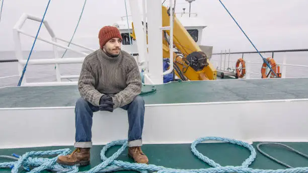 Lone Fisherman Sitting on Bench at the Commercial Ship.