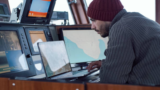 capitão do navio de pesca comercial cercado por monitores e telas que trabalham com mapas do mar em sua cabine. - seine net fotos - fotografias e filmes do acervo