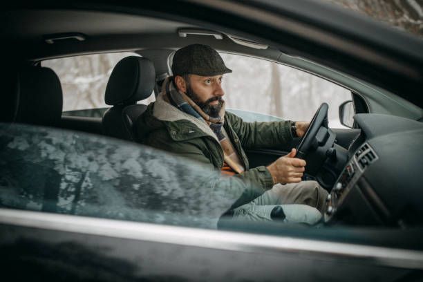 istock Man driving car in snowy forest 1169327606