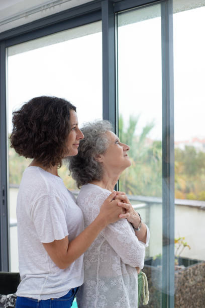 istock Pensive mother and daughter looking at window 1169327790