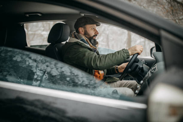 istock Man driving car in snowy forest 1169327791