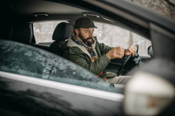 istock Man driving car in snowy forest 1169328183