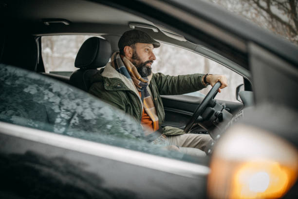 istock Man driving car in snowy forest 1169329660