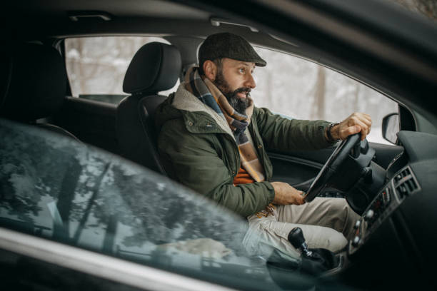 istock Man driving car in snowy forest 1169330859