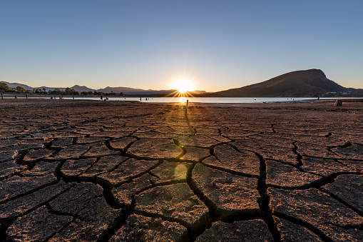 The sun sets setting over a lake it shows the dry cracks in lake bed. On a clear and sunny day in Lake Moogerah, Queensland, Australia.