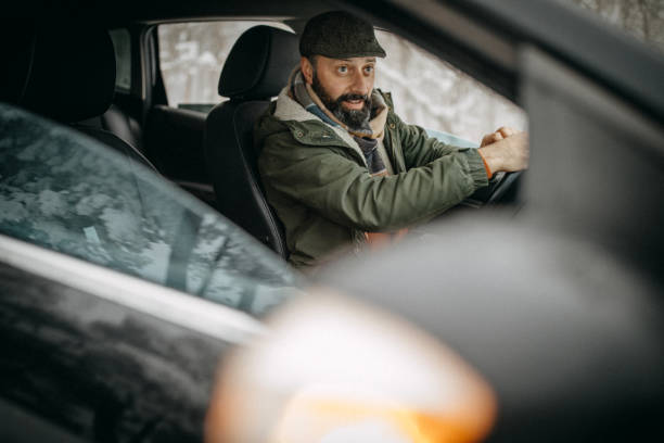 istock Man driving car in snowy forest 1169331132