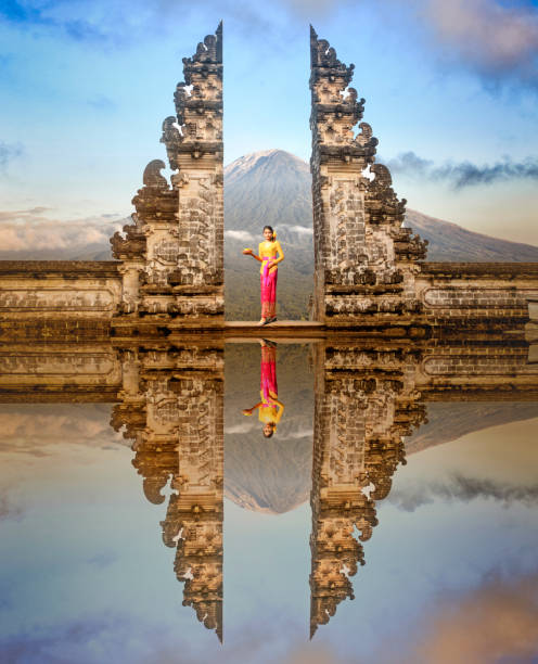 балийские женщины в традиционных костюмах стоят у ворот храма лемпуян на бали, индон�езия - ancient column past arch стоковые фото и изображения