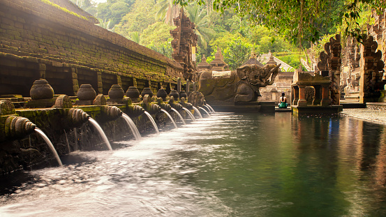 The holy spring water at the Tirta Empul temple near the city of Ubud, Bali, Indonesia, during a hot day on the tropical island.