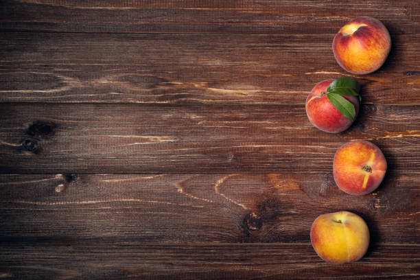 istock Fresh peaches with green leafs on brown wooden table 1169334809