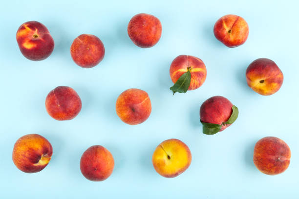 istock Fresh peaches with green leafs on blue background 1169334984