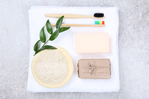 istock Bamboo toothbrushes with washcloth, soap and green leafs on gray background 1169337793