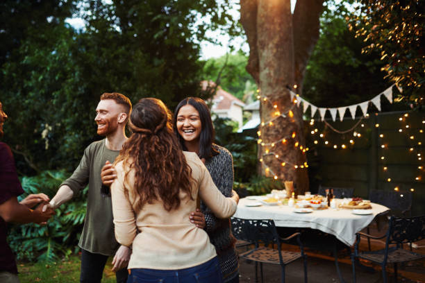 Shot of young friends greeting each other at a dinner party outdoors