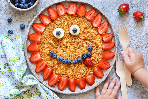 Food for children. Funny sun with a smile - pancakes with berries.