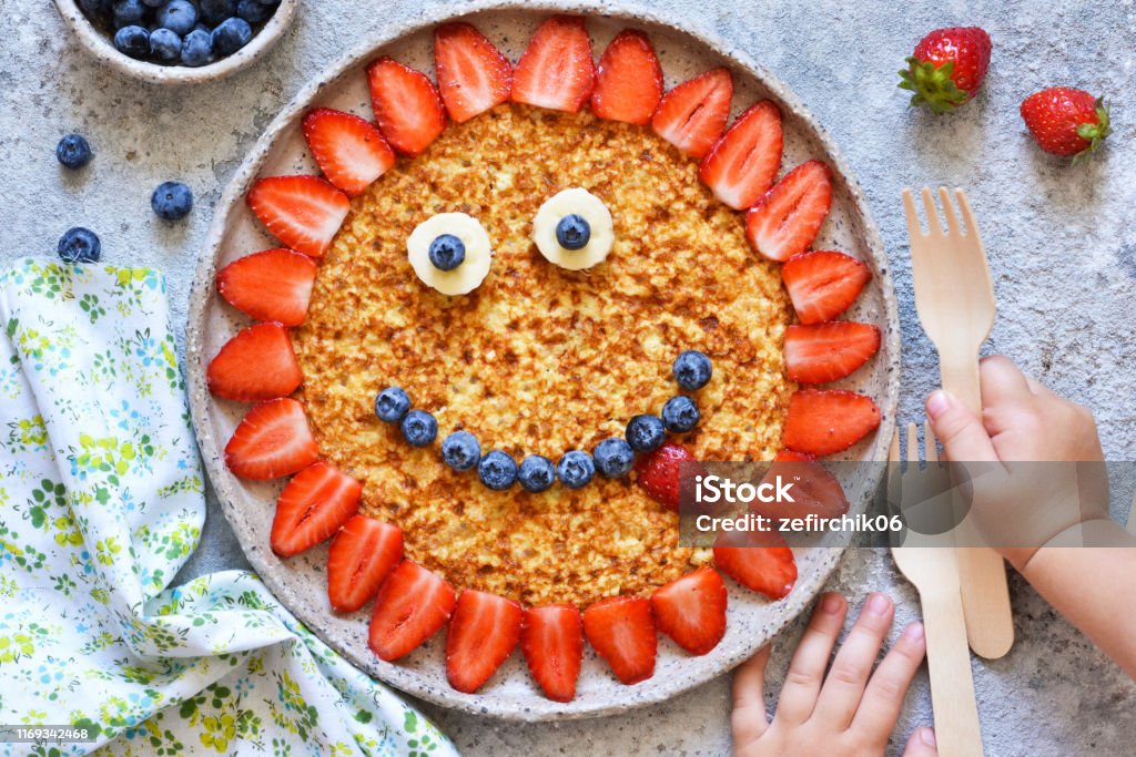 Food for children. Funny sun with a smile - pancakes with berries. Child Stock Photo