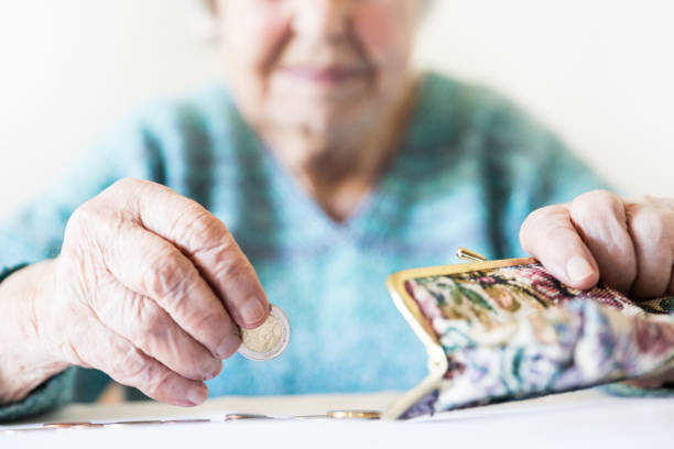 Detailed closeup photo of unrecognizable elderly womans hands counting remaining coins from pension in her wallet after paying bills. stock photo