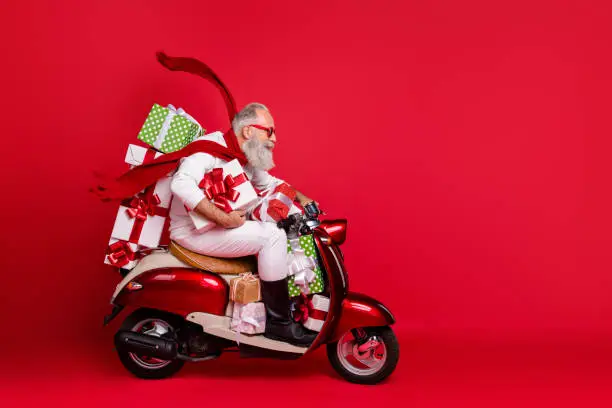 Photo of Profile side view of his he nice attractive trendy purposeful gray-haired man riding moto bike delivering pile stack purchase air wind blows isolated on bright vivid shine red background