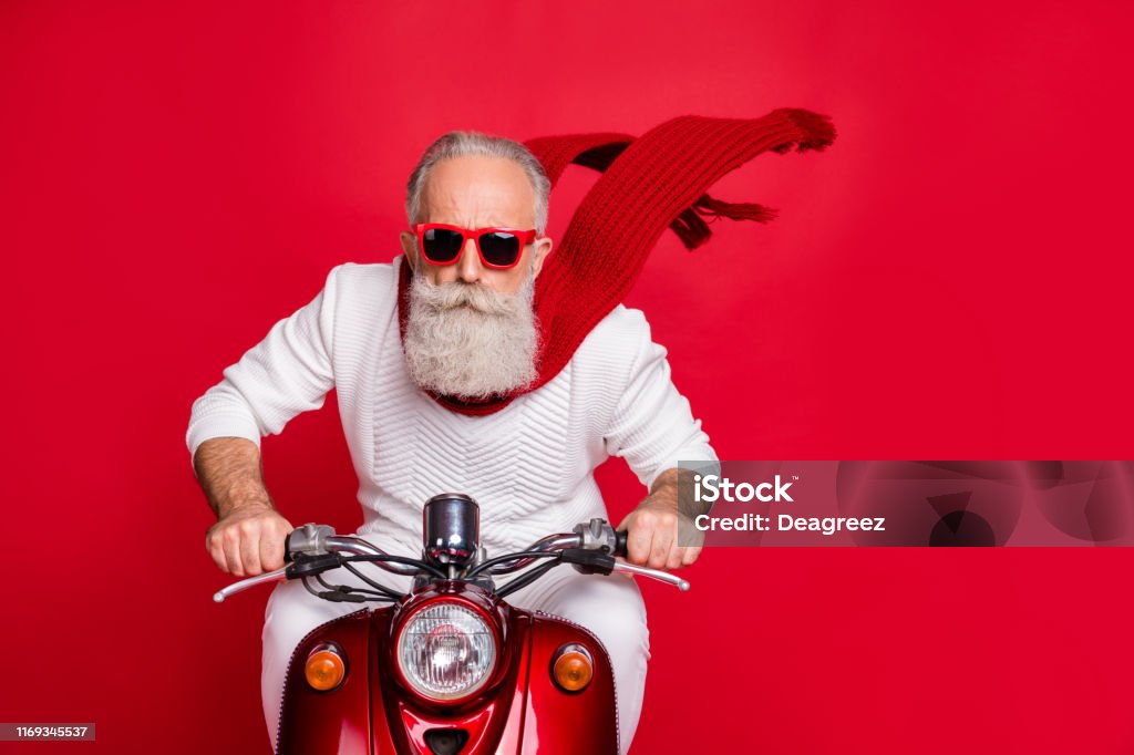 Feche acima da foto do pensionista fresco que monta sua bicicleta com o vento do ar que funde a camisola branca da ligação em ponte isolada sobre o fundo vermelho - Foto de stock de Natal royalty-free