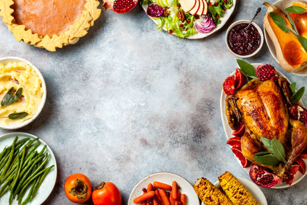 Thanksgiving dinner table with roasted whole chicken or turkey, green beans, mashed potatoes, cranberry sauce and grilled autumn vegetables. Top view, overhead.