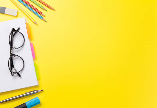 istock Office yellow backdrop with supplies and glasses 1169351034