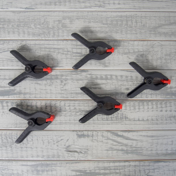 istock Several black and red spring clamps on the wooden boards 1169352162