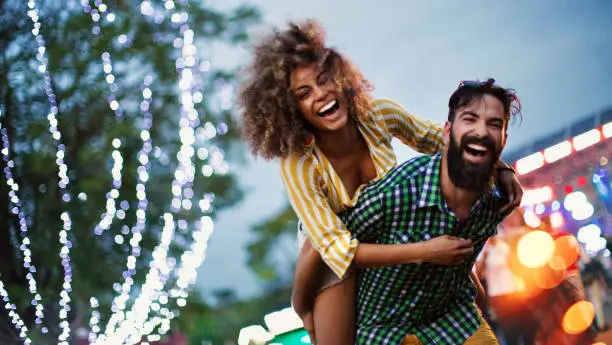 Young couple enjoying at music festival. They are laughing and looking at camera.