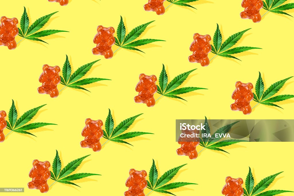 Pattern gummies in form of a bear with CBD oil on a yellow background. Minimum CBD concept Trend sunlight CBD pattern with green leaf cannabis and gummies on light blue background. Minimal CBD OIL concept Gummy Candy Stock Photo