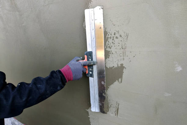 istock Worker covering insulated wall with solution of glue over plastered styrofoam insulation. 1169367676